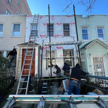 professionals climbing up the house for starting roofing work using ladders and vehicle.